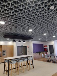 Contemporary office interior showcasing unique grid-patterned ceiling and minimalist furniture for a stylish workspace.